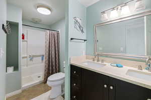 Full bathroom with double vanity, a stall shower, and light tile patterned floors