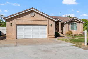 Single story home with stucco siding, a tiled roof, driveway, and an attached garage