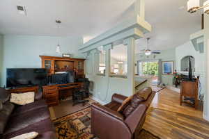 Living room featuring a chandelier, a desk, wood finished floors, lofted ceiling, and a ceiling fan