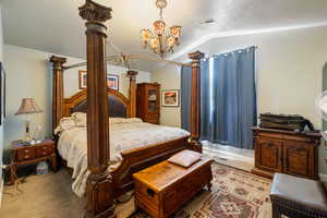 Carpeted bedroom featuring vaulted ceiling, a textured ceiling, and a chandelier