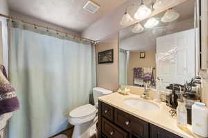 Bathroom featuring a textured ceiling, vanity, and curtained shower