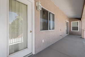 Doorway to property with a patio area, stucco siding, and crawl space