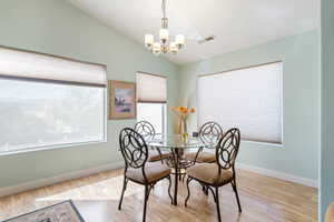 Dining space with vaulted ceiling, light wood-style floors, and a chandelier