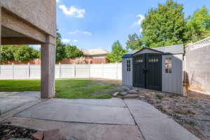 Fenced backyard with a patio area and a shed