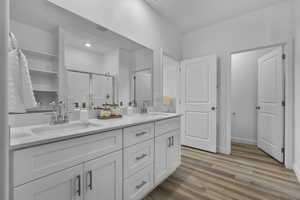 Bathroom featuring a stall shower, double vanity, and light wood-style flooring