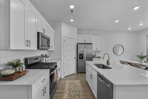 Kitchen featuring stainless steel appliances, dark wood-type flooring, white cabinetry, recessed lighting, and a kitchen island with sink