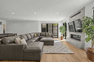 Living area with light wood-style floors, recessed lighting, and a high end fireplace
