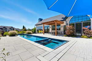 View of swimming pool featuring a pool with connected hot tub, a patio area, and a pergola
