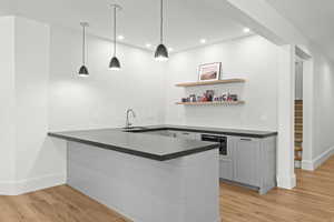 Indoor wet bar with open shelves, gray cabinetry, light wood-type flooring, pendant lighting, and stairs