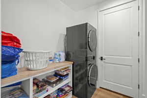 Laundry area featuring stacked washer and clothes dryer and light wood-type flooring