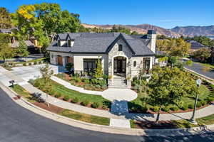 French provincial home with stone siding, a chimney, a mountain view, and concrete driveway