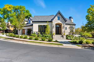 French country style house with stone siding, a chimney, stucco siding, and a high end roof