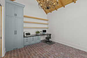 Office featuring built in desk, brick floors, wooden ceiling, and a chandelier
