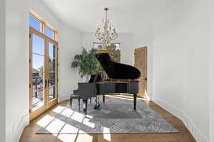 Living area with wood finished floors, a chandelier, and french doors