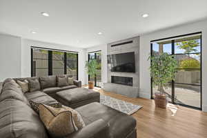 Living room with wood finished floors, recessed lighting, and a fireplace