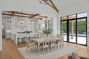 Dining space featuring beamed ceiling, light wood-style flooring, coffered ceiling, recessed lighting, and a chandelier
