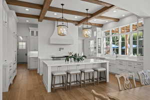 Kitchen with glass insert cabinets, a kitchen breakfast bar, pendant lighting, white cabinets, and backsplash