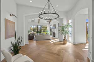 Entryway with a fireplace, a chandelier, arched walkways, a towering ceiling, and recessed lighting