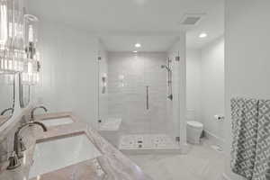 Bathroom featuring a stall shower, double vanity, and recessed lighting