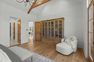 Bedroom featuring light wood-style floors, high vaulted ceiling, and beam ceiling