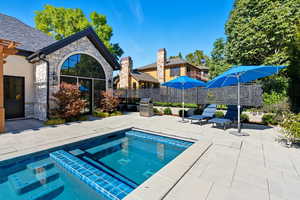 View of swimming pool featuring a patio area, a pool with connected hot tub, and an outdoor kitchen