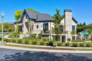 French country home with stone siding, a chimney, and stucco siding