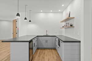 Kitchen featuring backsplash, decorative light fixtures, light wood finished floors, a peninsula, and open shelves