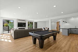 Playroom with light wood-style floors, recessed lighting, healthy amount of natural light, billiards, and bar with sink