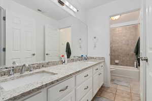 Bathroom featuring double vanity,  shower combination, and light tile patterned floors