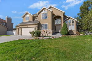 View of front of property with concrete driveway, stucco siding, stone siding, and an attached garage