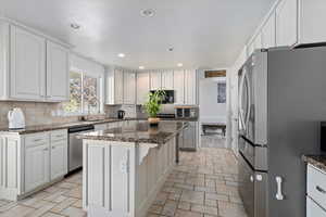Kitchen featuring appliances with stainless steel finishes, tasteful backsplash, dark stone counters, and recessed lighting