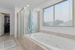 Full bath featuring a shower stall, a walk in closet, a tub with jets, light tile patterned flooring, and recessed lighting