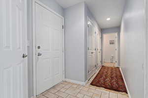 Hallway with light tile patterned floors and recessed lighting