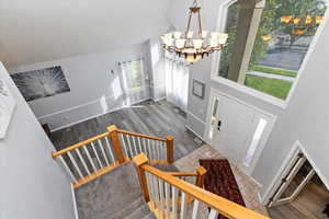 Entrance foyer with high vaulted ceiling, wood finished floors, stairs, and a chandelier