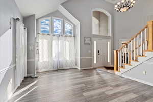 Foyer entrance featuring light wood-style floors, high vaulted ceiling, a chandelier, and stairs