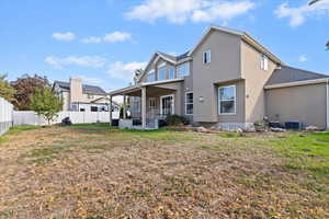 Rear view of house with stucco siding, a fenced backyard, and covered porch