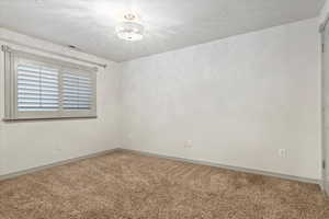 Carpeted empty room with baseboards and a textured ceiling