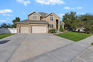 Traditional home featuring stucco siding, stone siding, driveway, and an attached garage
