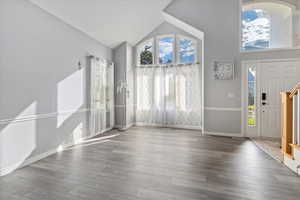 Foyer entrance featuring high vaulted ceiling and wood finished floors