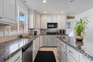 Kitchen with dark stone countertops, dishwasher, recessed lighting, black microwave, and light tile patterned floors
