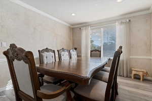Dining space with crown molding, light wood-style floors, and recessed lighting