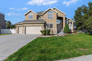 Traditional home with stone siding, stucco siding, concrete driveway, and a garage