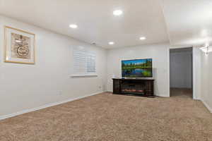 Unfurnished living room with light carpet, recessed lighting, and a glass covered fireplace