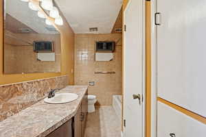 Bathroom with tile walls, decorative backsplash, vanity, shower / bath combination, and a textured ceiling