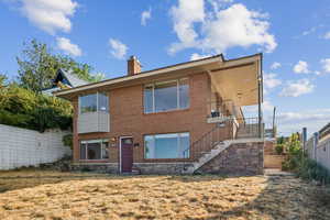 View of front of house featuring a chimney, stairway, and brick siding