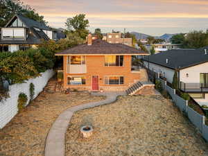 View of front of property featuring stairs, a fenced backyard, a chimney, brick siding, and a mountain view