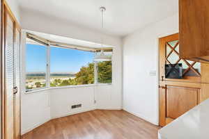 Unfurnished dining area with light wood-style flooring and baseboards