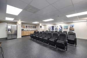 Home theater with a drop ceiling and baseboards