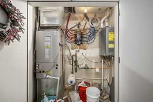 Utility room featuring tankless water heater and heating unit
