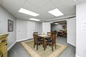 Carpeted dining room featuring baseboards and a drop ceiling
